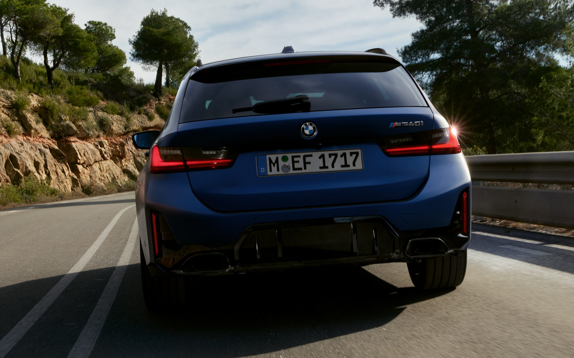 BMW M340i xDrive Touring G21 rear view driving on the street BMW M340i xDrive Touring G21 Frozen Tanzanite Blue rear view driving on the street