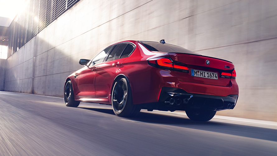 BMW M5 Competition F90 LCI Facelift 2020 three-quarter rear view driving BMW M5 Competition F90 LCI Facelift 2020 BMW Individual Imola Red three-quarter rear view driving