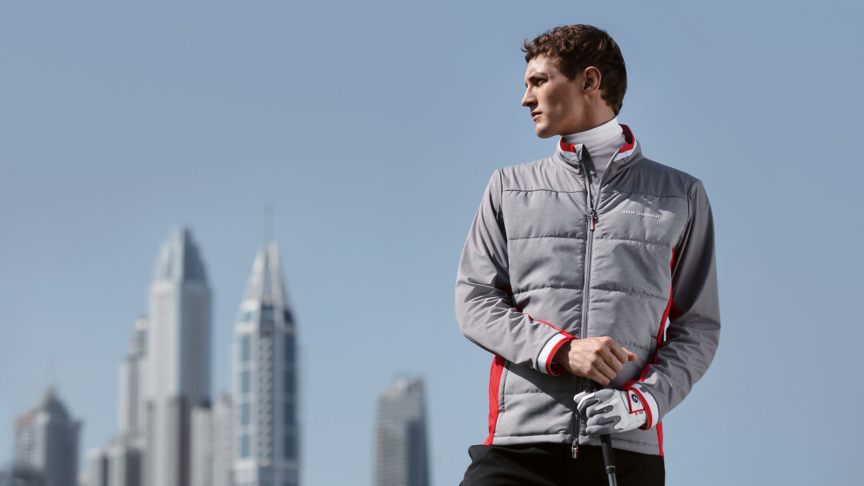 A male model presents products from the BMW Golfsport Collection against a backdrop of a big city skyline. A male model presents products from the BMW Golfsport Collection against a backdrop of a big city skyline.
