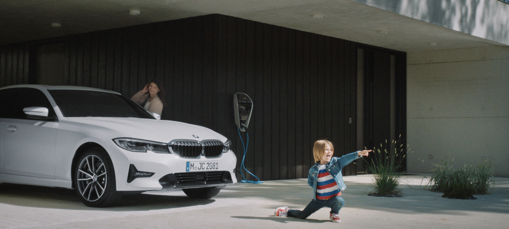 BMW hybrid vehicle at charging station BMW plug-in hybrids boy in front of BMW hybrid vehicle at charging station