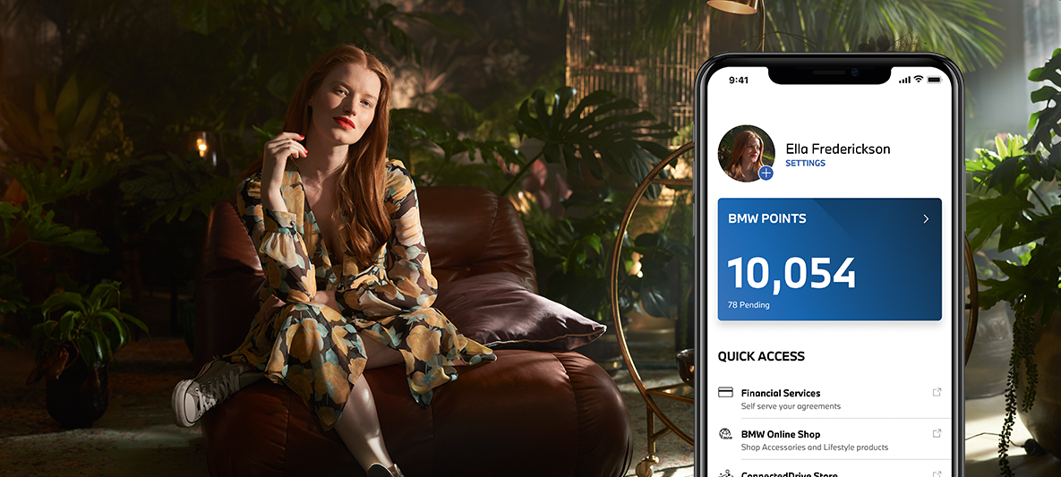 My BMW App electric driving and collecting BMW Points woman sitting on an armchair in front of plants My BMW App electric driving and collecting BMW Points woman sitting on an armchair in front of plants
