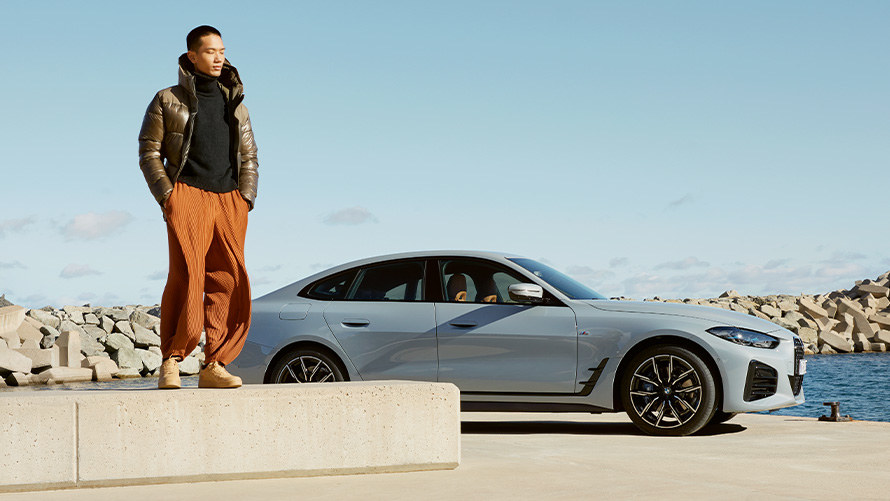 BMW Service Inclusive BMW Service Inclusive BMW G26 Man standing on stone edge with BMW vehicle in background
