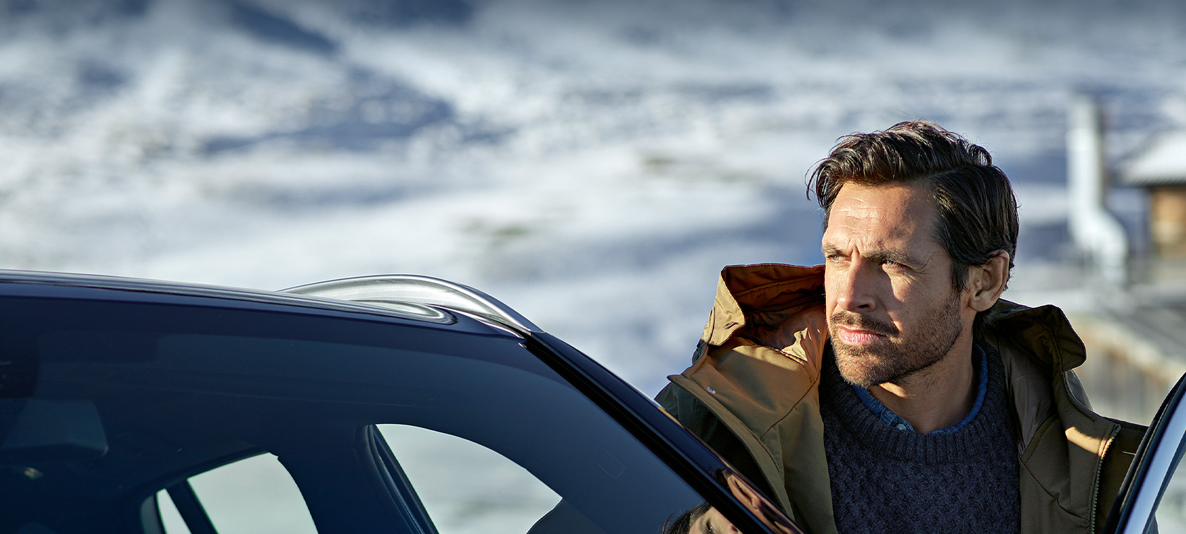 Man with winter parka standing in the door of his BMW Original BMW Accessories and BMW Services for autumn and winter