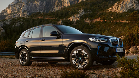 BMW i Series BMW iX3 three-quarter side view standing in front of mountain landscape