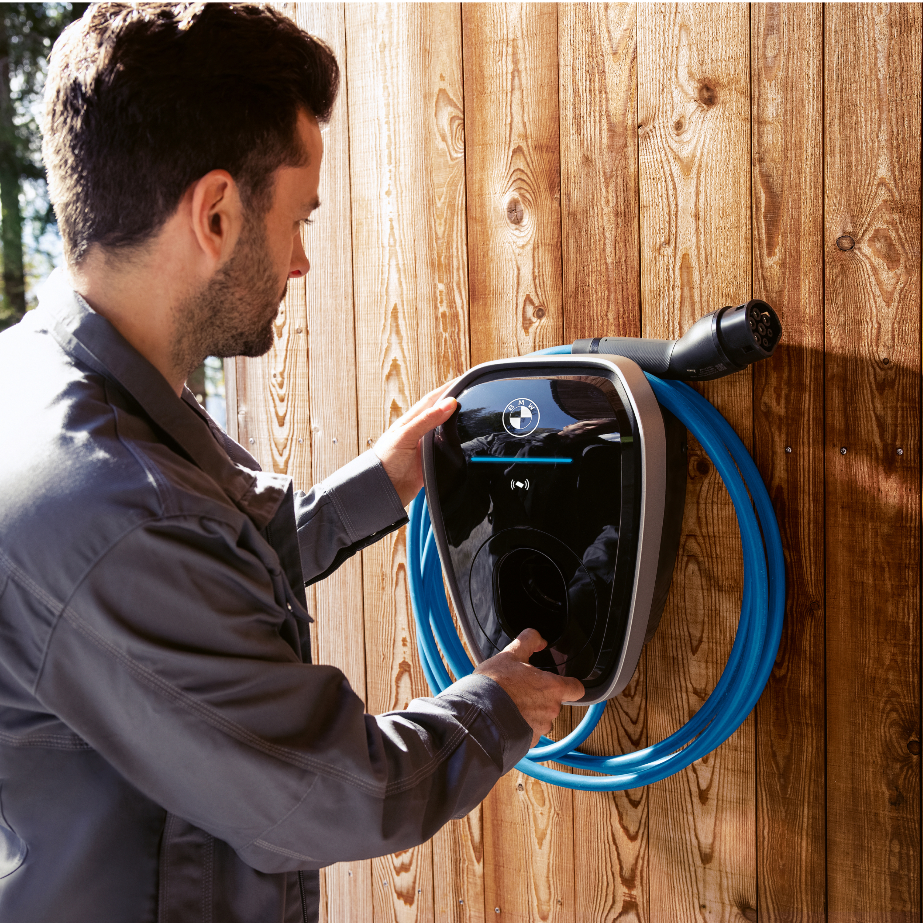 A person is connecting a charging cable to a BMW wallbox